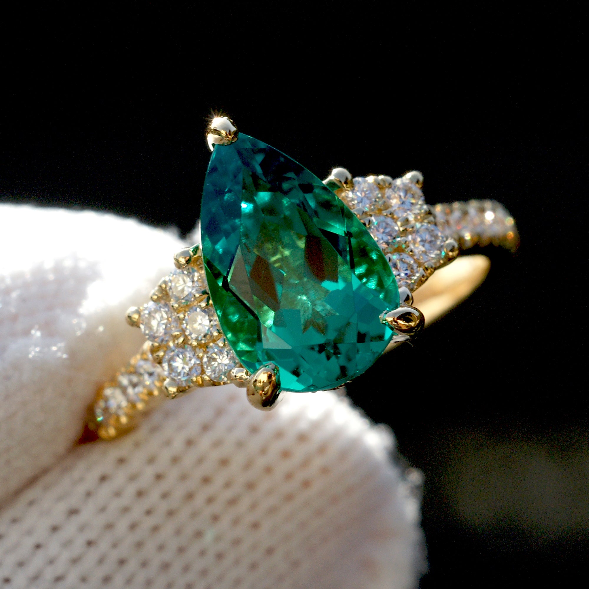 Pear emerald three stone ring with trapezoid side diamond shape in yellow gold
