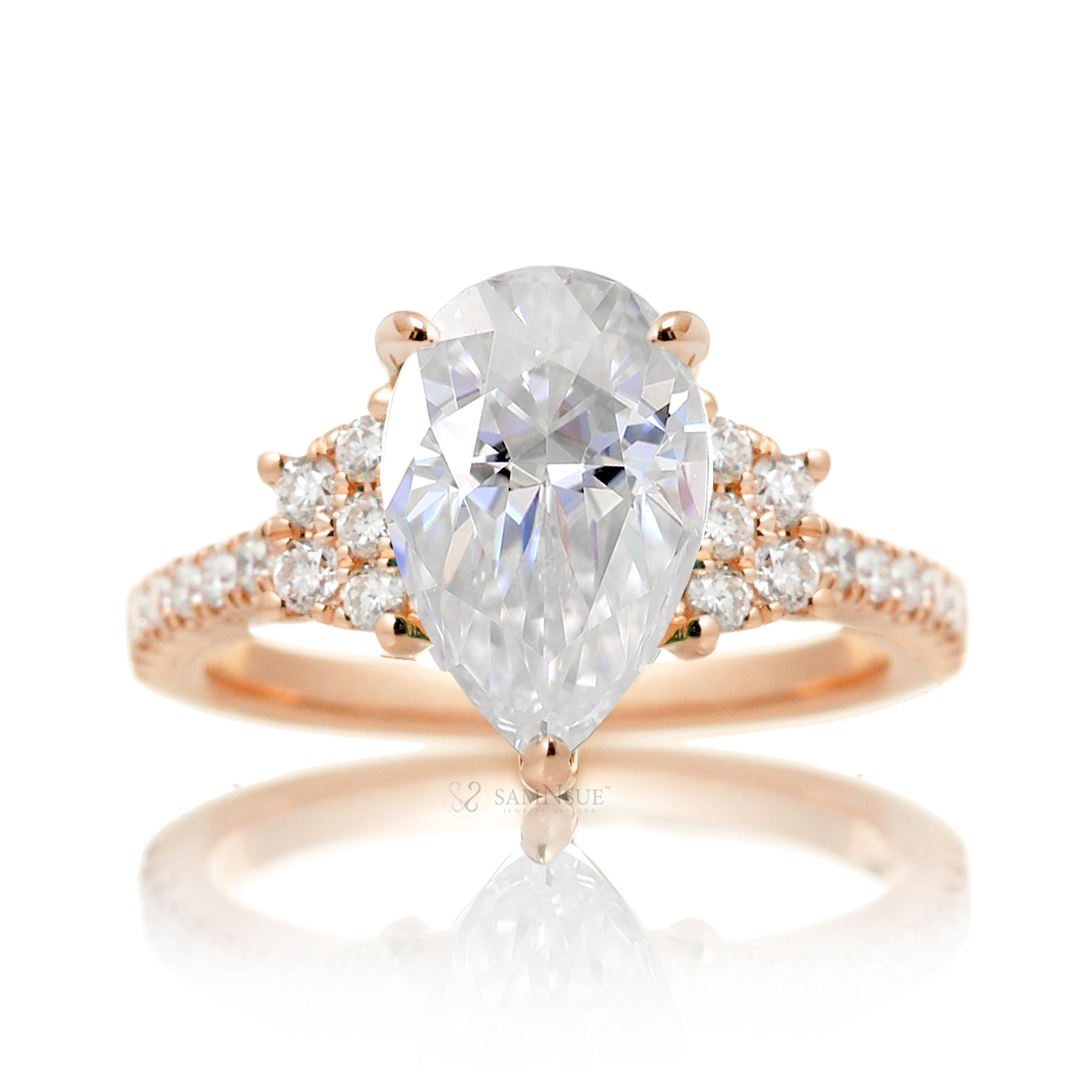 Moissanite three stone ring with pear cut center stone and diamond trapezoid accent in rose gold