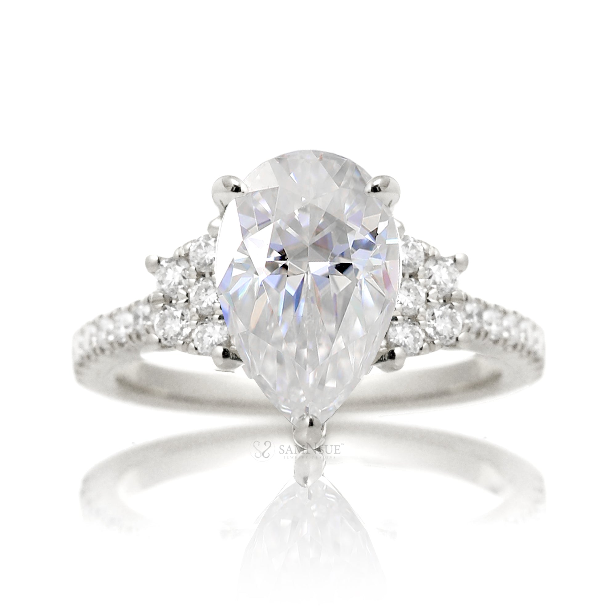 Moissanite three stone ring with pear cut center stone and diamond trapezoid accent in white gold