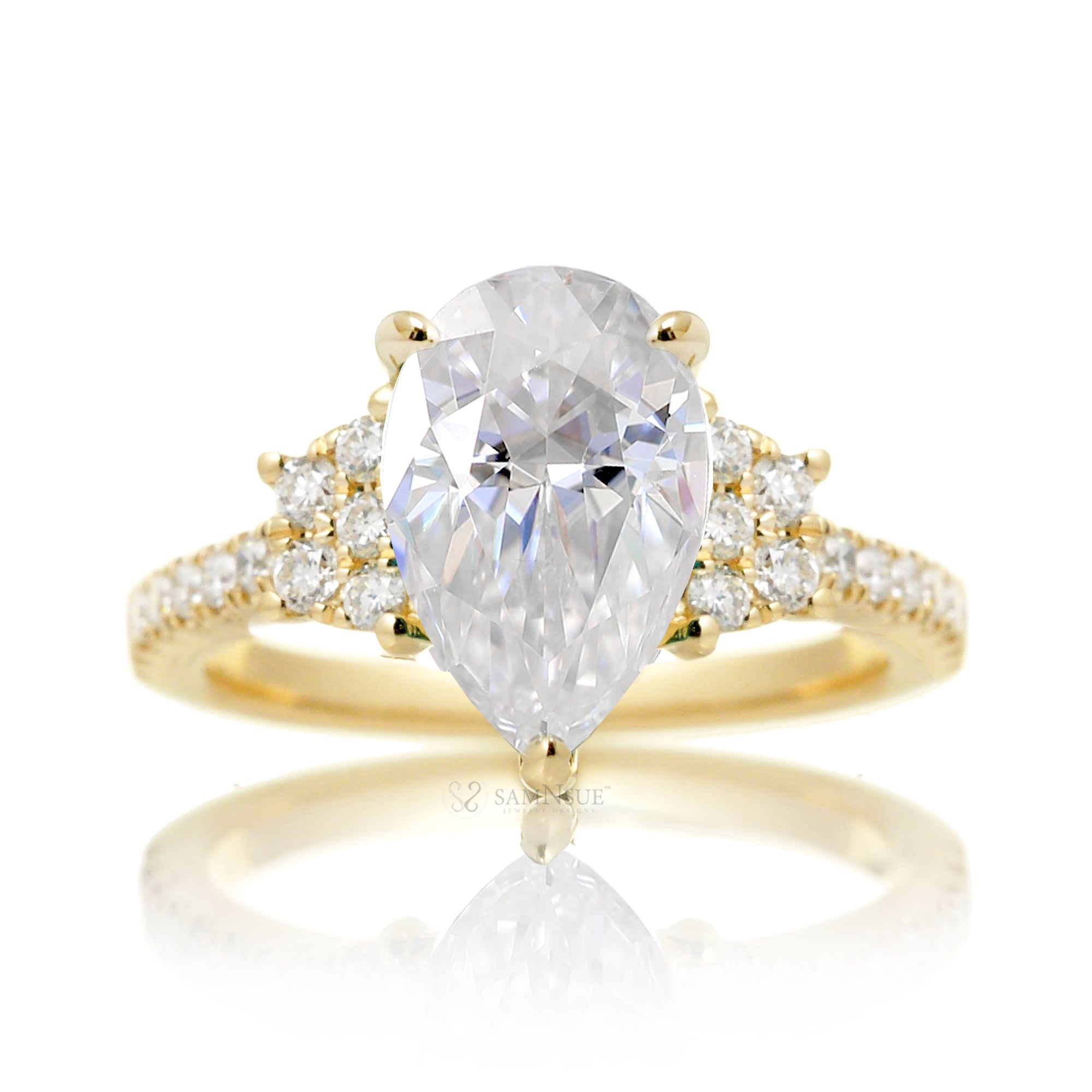 Moissanite three stone ring with pear cut center stone and diamond trapezoid accent in yellow gold