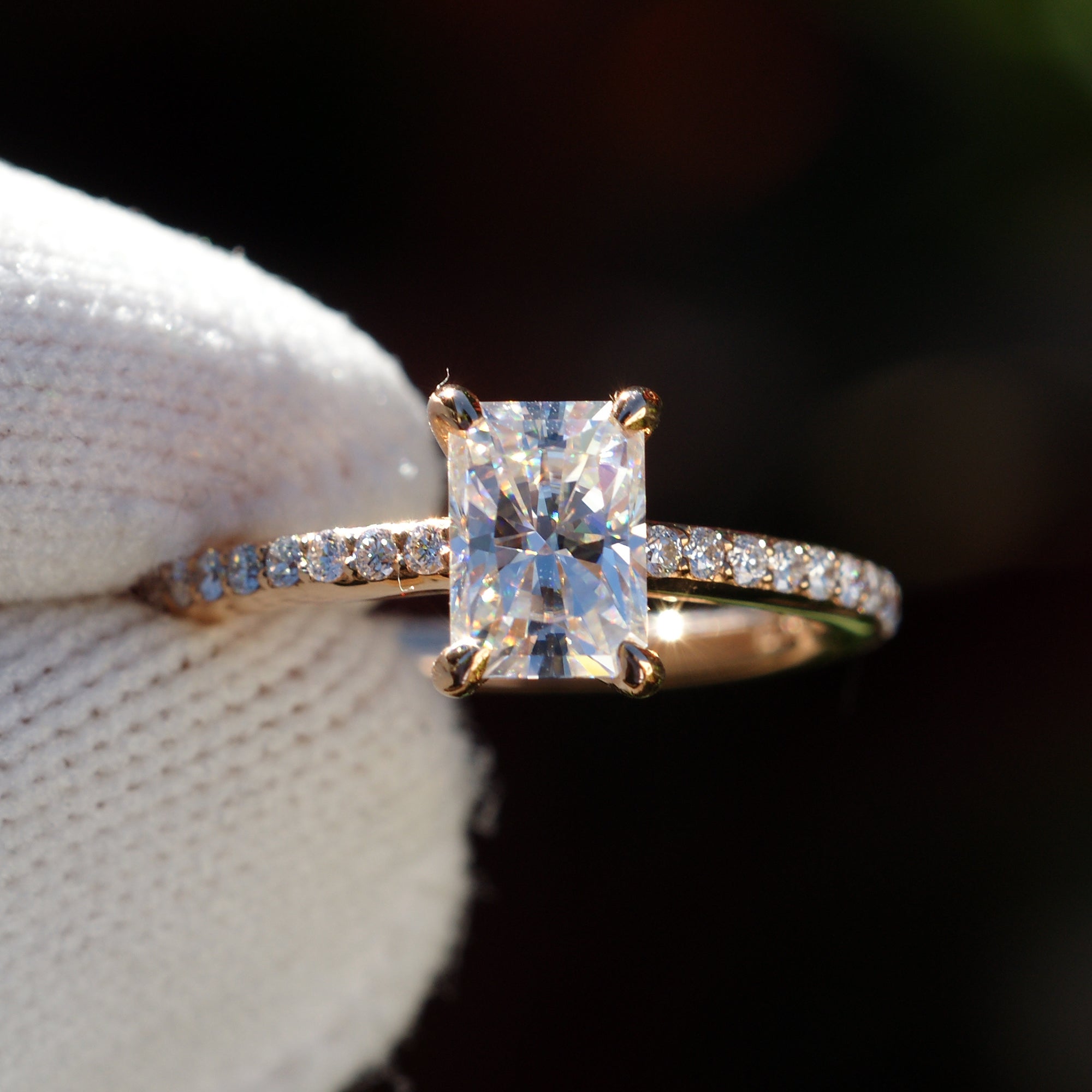 Radiant cut moissanite ring in rose gold with diamond accent on band, top view