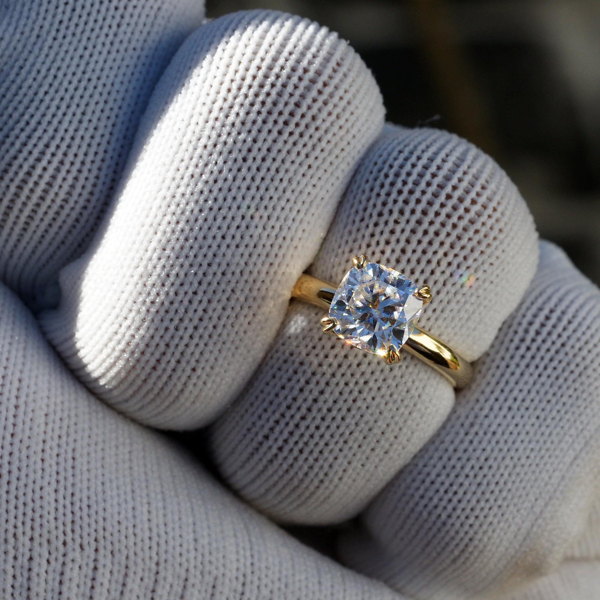 Cushion cut moissanite solitaire engagement ring in yellow gold The Leila on finger