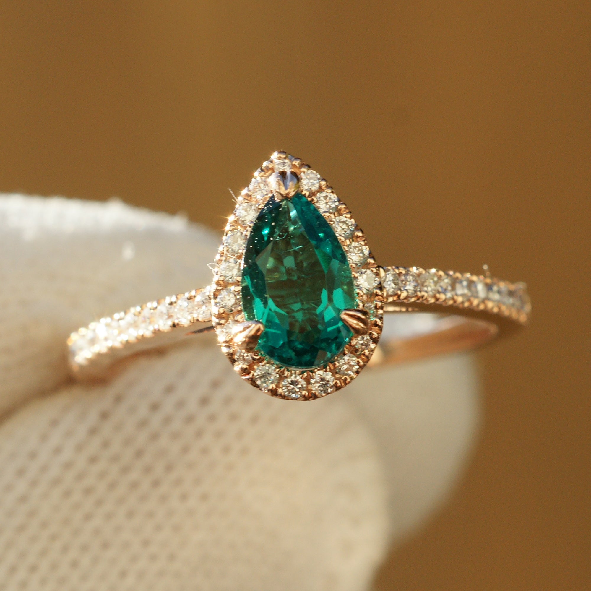 Pear cut emerald diamond halo engagement ring with the signature 8x5mm rose gold