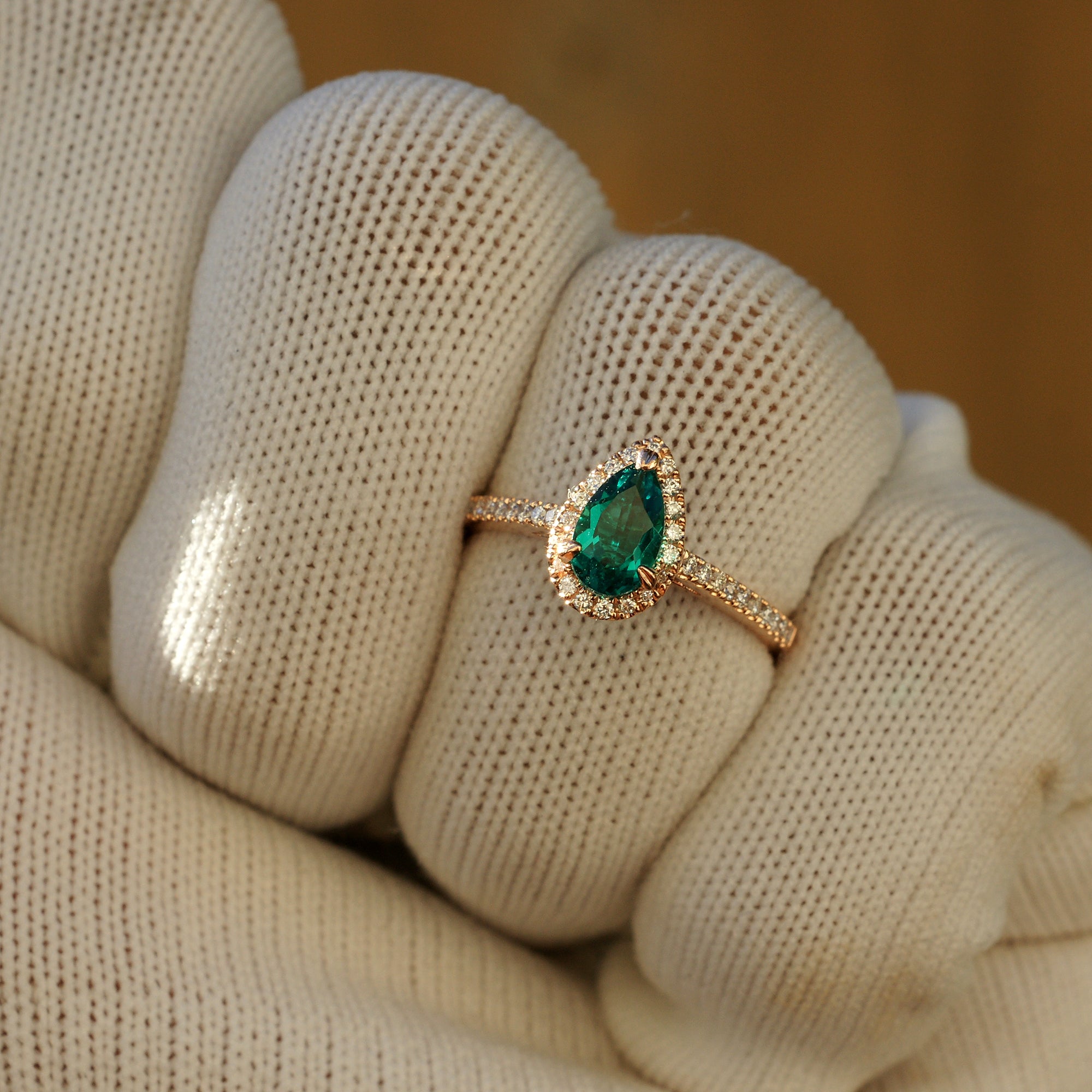 Pear cut emerald diamond halo engagement ring with the signature 8x5mm rose gold