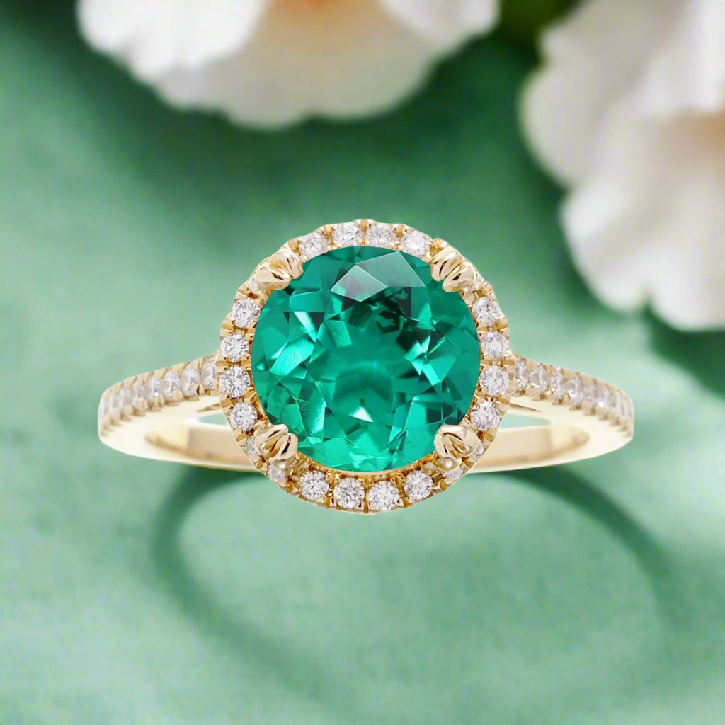 Round cut emerald ring with a diamond halo in yellow gold