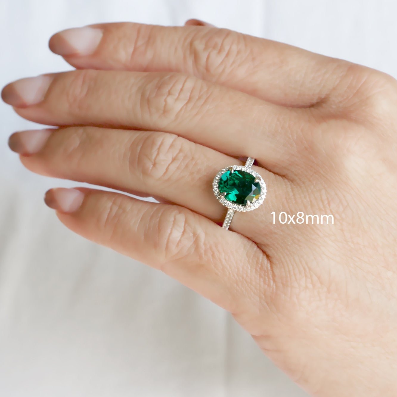 Oval cut green emerald engagement ring with a diamond halo in rose gold